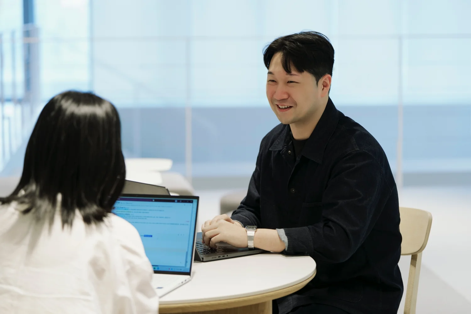 앳홈 팀원이 밝은 라운지에서 노트북을 앞에 두고 웃으며 대화하는 모습