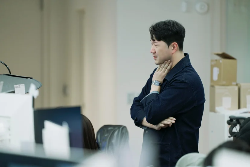 앳홈 팀원이 사무실에서 팔짱 끼고 생각에 잠긴 모습