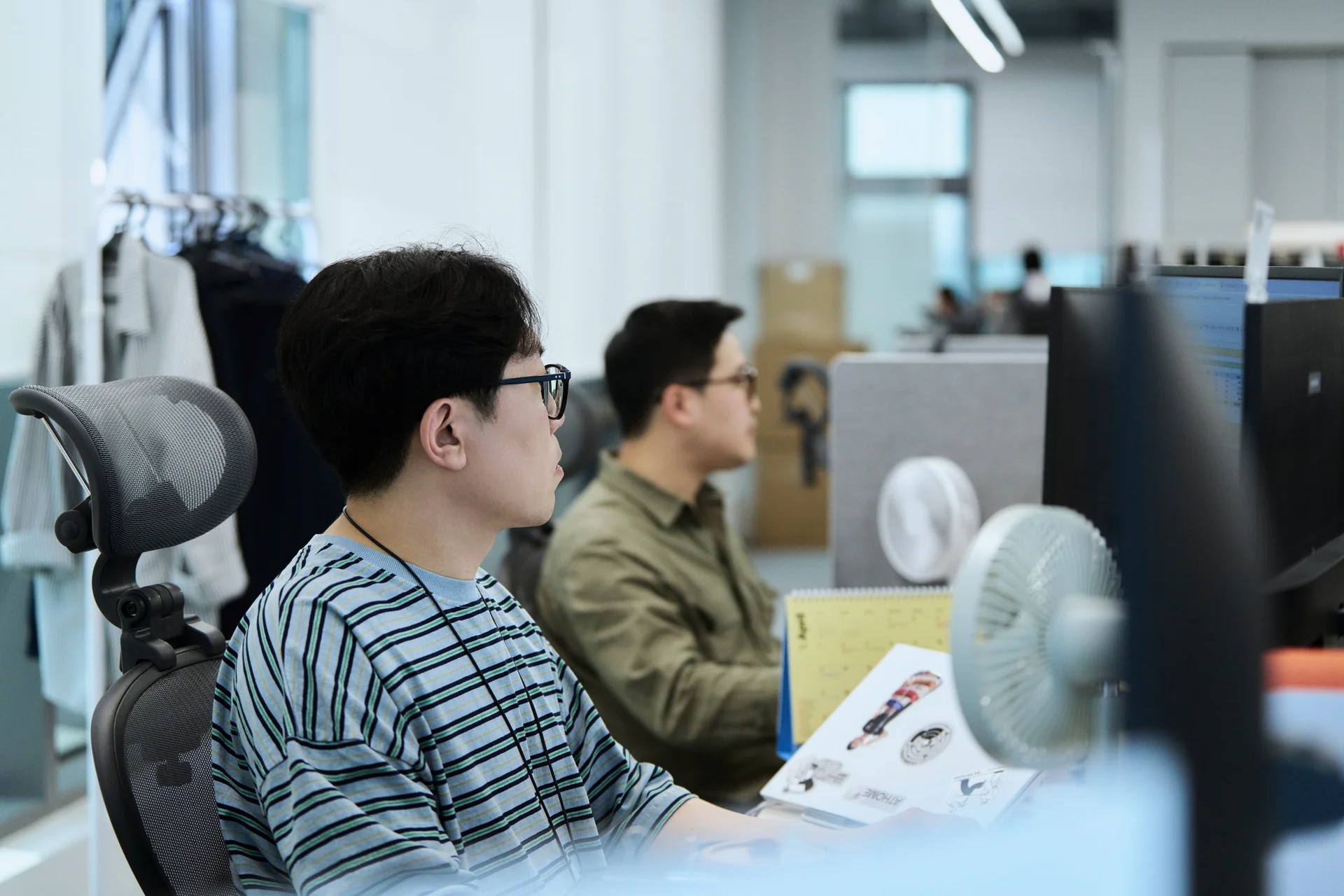 스트라이프 티를 입은 이정우님(남성)이 오피스 자리에 앉아 있다