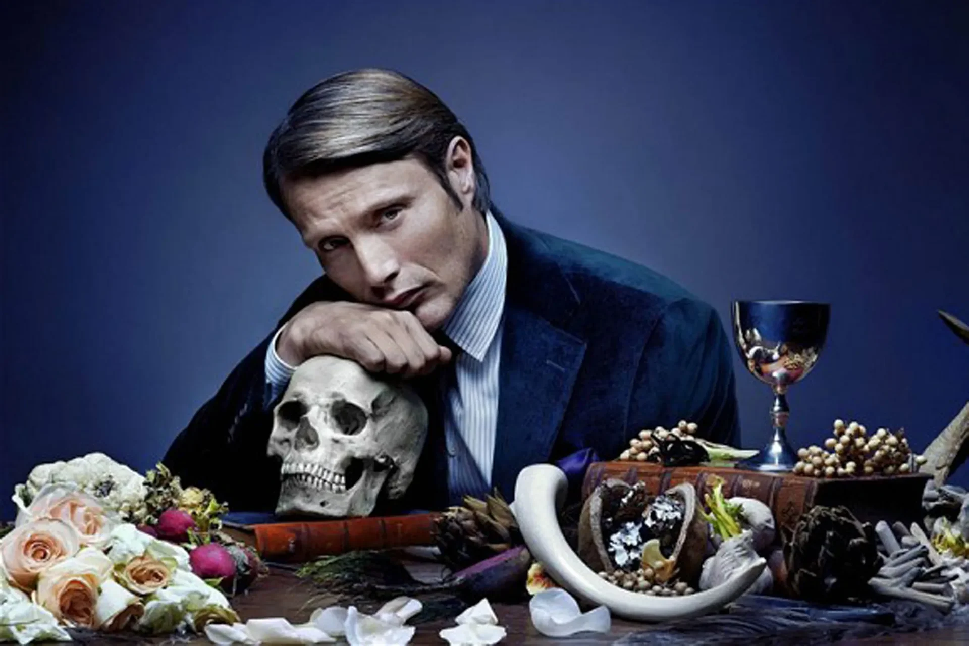 Hannibal Lecter in a dark suit resting beside a skull, a classic example of a psychologically complex villain in fiction.