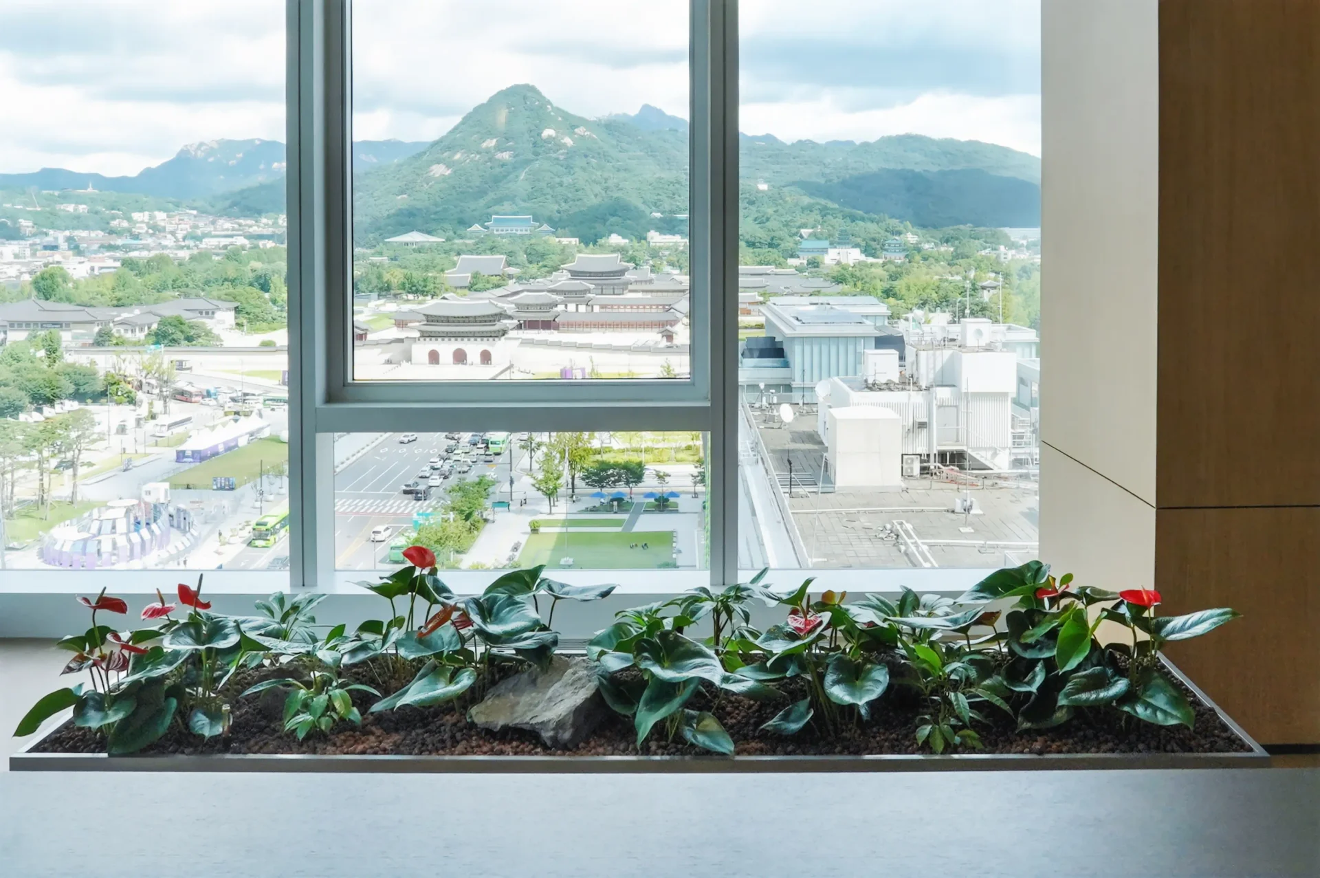 북악산과 경복궁이 내려다보이는 고층 라운지. 소엽 관목을 낮게 군식해 조망을 살리면서 실내에 자연의 층위를 더했다.