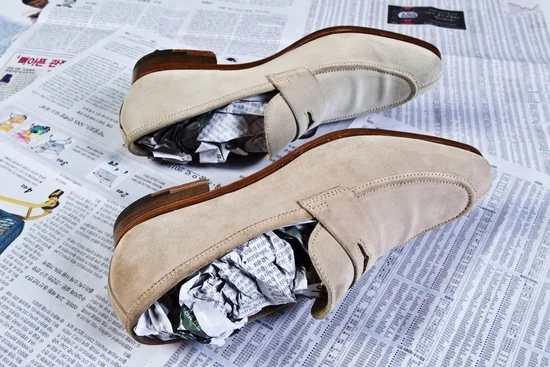 Beige suede loafers stuffed with newspaper for dehumidification
