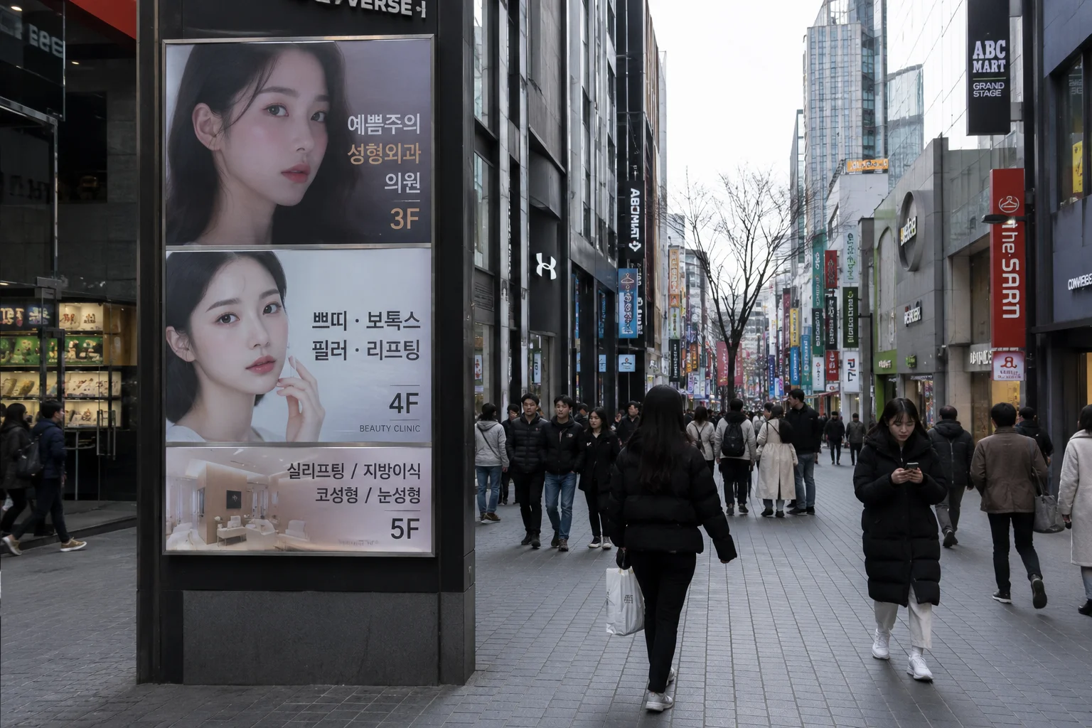 A busy shopping street in South Korea with tall buildings, bright signs, and people walking in winter clothes.