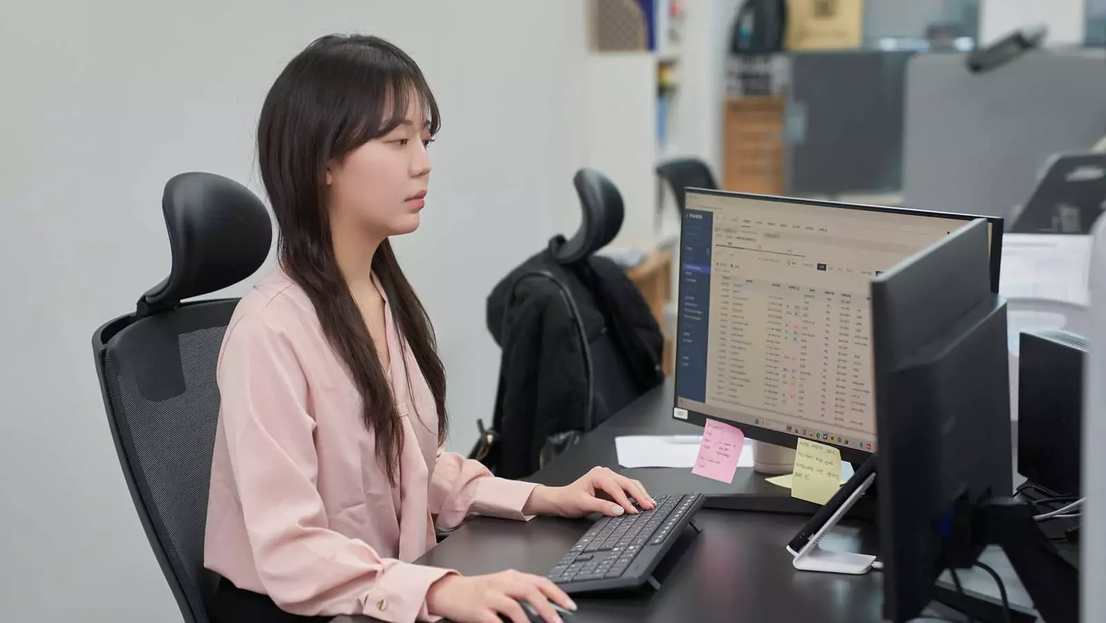 데스크에 앉아 PC 화면을 보며 ERP 프로그램을 사용 중인 직원
