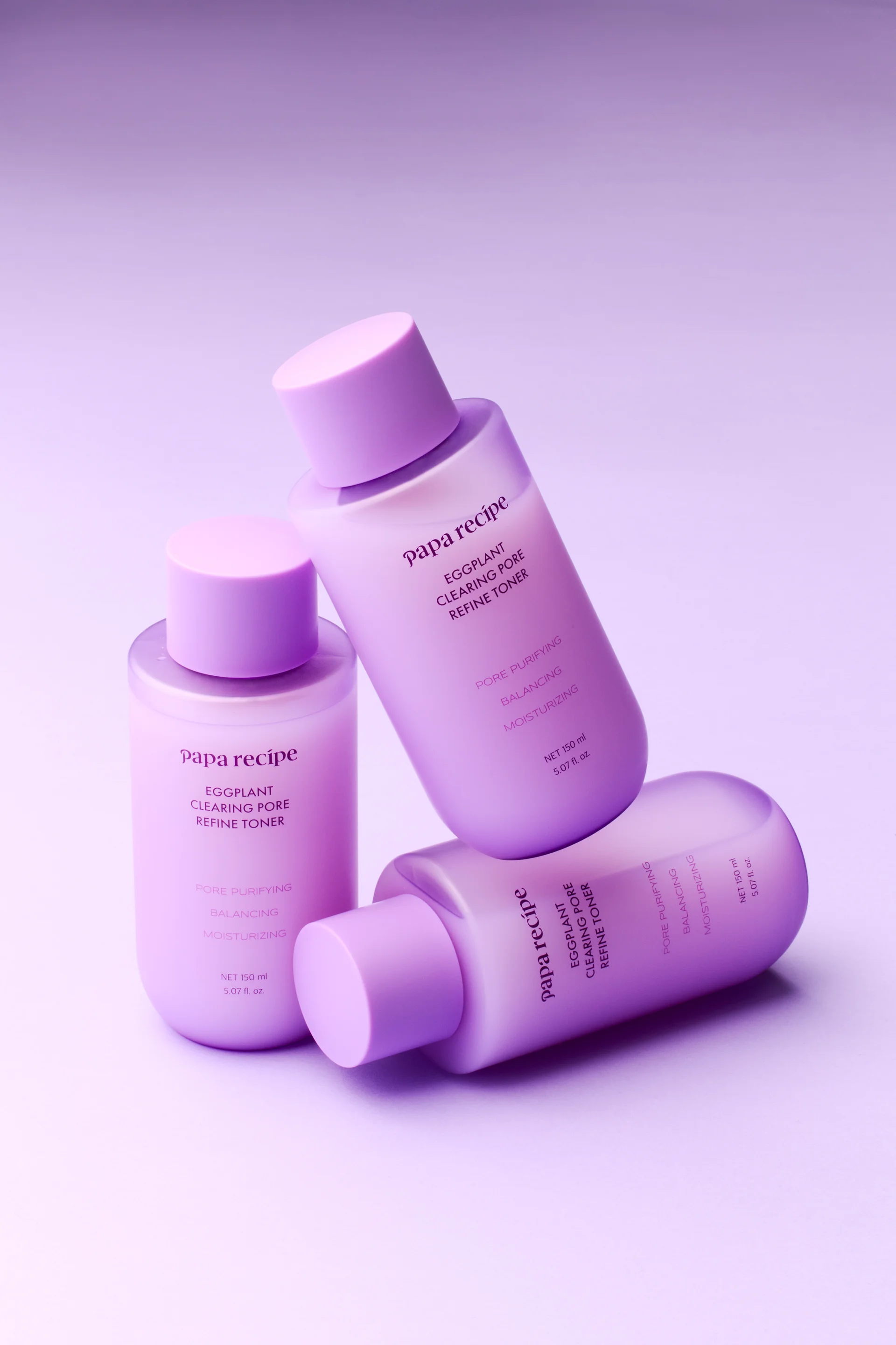 Three bottles of Papa Recipe Eggplant Clearing Pore Refine Toner 150ml arranged together against a lavender background, labeled with pore purifying, balancing, and moisturizing