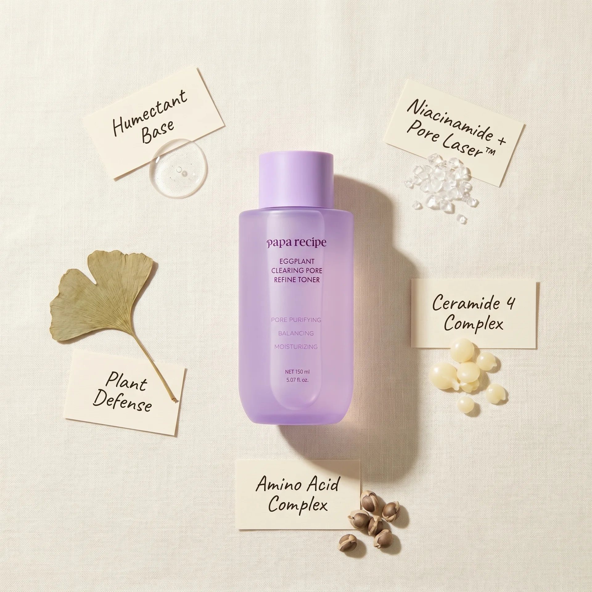 Papa Recipe Eggplant Clearing Pore Refine Toner 150ml bottle centered on a linen surface, surrounded by handwritten ingredient labels — Humectant Base, Niacinamide + Pore Laser™, Plant Defense, Ceramide 4 Complex, and Amino Acid Complex — each paired with corresponding ingredient props