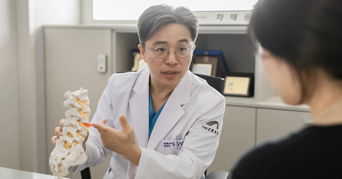 진료실에서 척추 모형으로 환자에게 허리디스크에 대해서 설명을 하는 차재룡 병원장