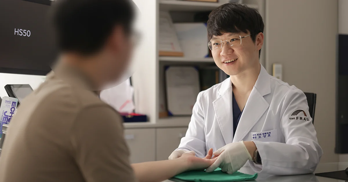더프라우병원 수부외과 오상호 원장이 수부질환이 있는 환자의 손을 촉진하며 진료 상담을 하는 장면