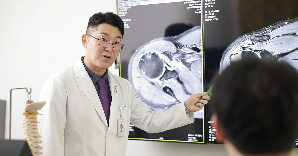 더프라우병원의 정형외과 전문의 황철호 원장이 모니터에 환자의 어깨 관절 MRI 영상을 띄워서 회전근개 파열에 대해서 설명하는 장면