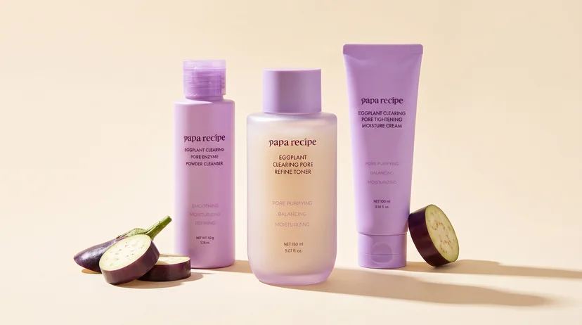 Three Papa Recipe Eggplant Clearing Pore line products displayed together on a cream background with halved eggplant — Eggplant Clearing Pore Enzyme Powder Cleanser 50g, Eggplant Clearing Pore Refine Toner 150ml, and Eggplant Clearing Pore Tightening Moisture Cream 100ml