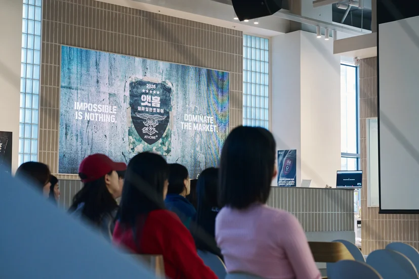 'IMPOSSIBLE IS NOTHING, DOMINATE THE MARKET' 슬로건 화면을 바라보는 앳홈 구성원들
