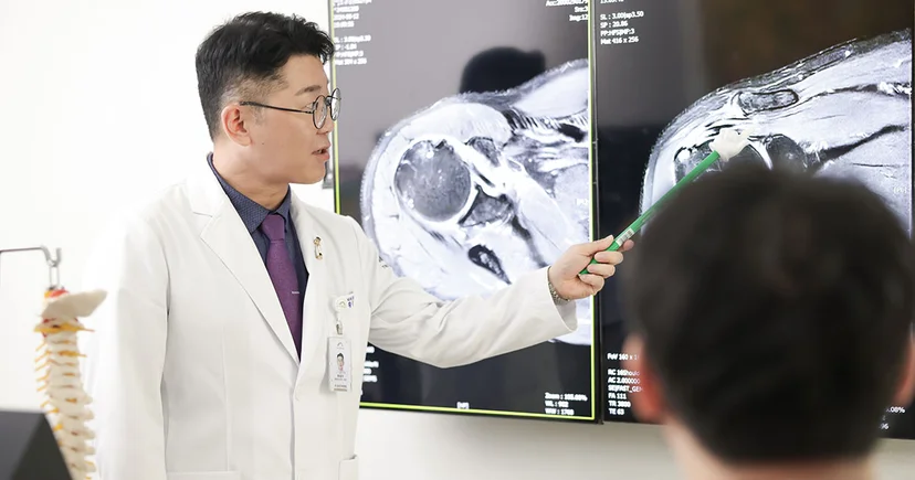 진료실 모니터에 띄운 정밀 MRI 영상을 보며 황철호 원장이 오십견으로 굳은 관절낭과 석회화 건염 병변의 명확한 차이점을 비교 설명하는 모습