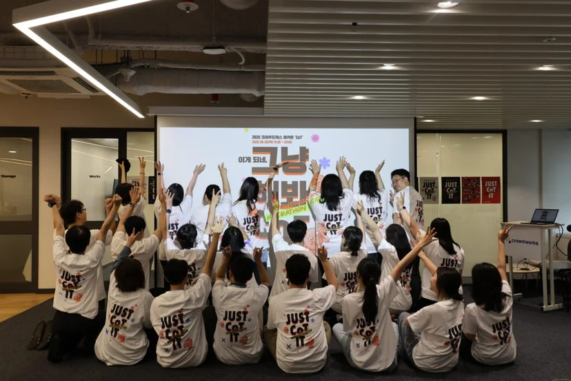 사내 해커톤에 참여한 구성원들이 동일한 유니폼을 입고 단체 사진을 찍고 있는 이미지