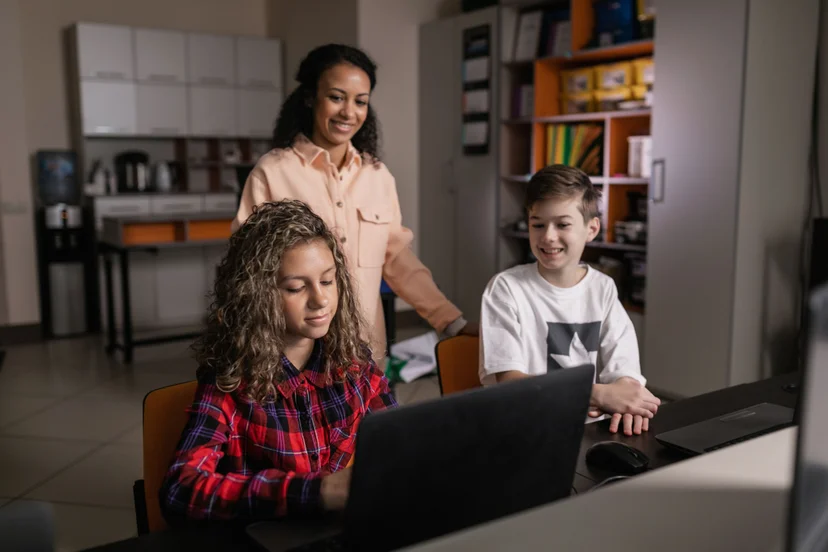 Teacher helps two students play an online whiteboard game.