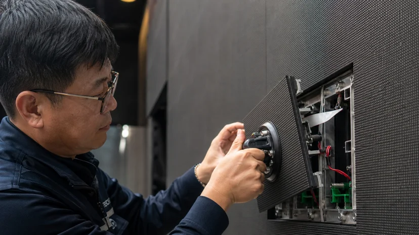 켜져 있는 LED 화면의 앞면에서 고장 모듈만 흡착 공구로 분리하는 전면 유지보수 작업 모습
