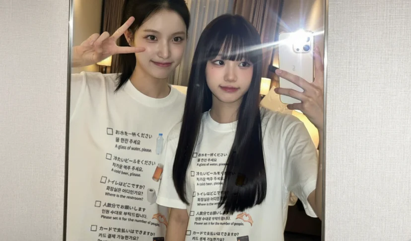 마플 커스텀 여행 티셔츠 – 여행 중 사용할 수 있는 일본어·한국어·영어 문구와 아이콘을 인쇄한 흰색 반팔 티셔츠를 맞춰 입고 거울 셀카를 촬영한 여성 2명의 이미지