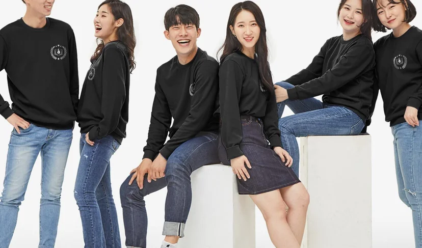만상사 단체 유니폼 – 원형 팀 로고를 가슴에 인쇄한 검은색 맨투맨을 남녀 구성원 6명이 맞춰 입고 흰 배경에서 촬영한 이미지