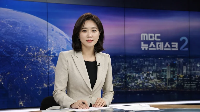 대형 LED 비디오월을 배경으로 방송을 진행하는 뉴스 스튜디오의 앵커