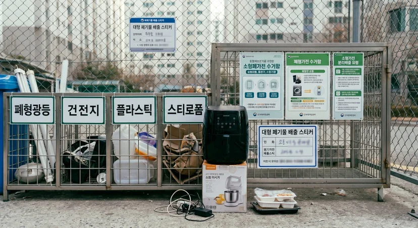 아파트 분리수거장 분리수거함 철제망 앞에 놓인 블랙 에어프라이어