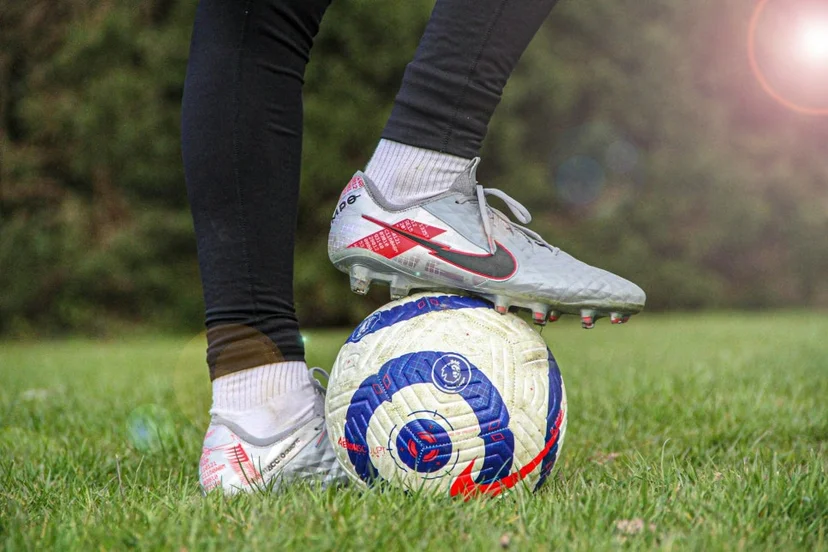 잔디밭 축구공 위에 축구화를 얹고 스탠딩 자세를 취한 축구선수의 발