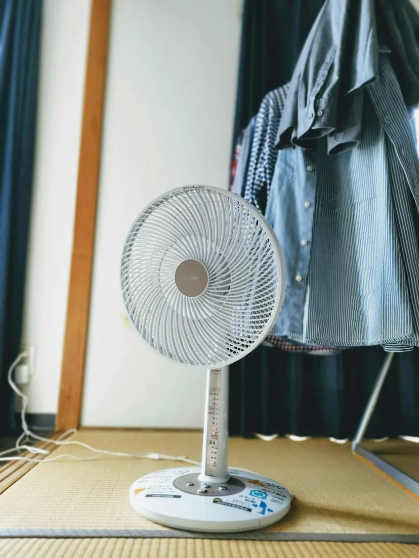 다타미 바닥 위에 세워져 있는 흰색 스탠드 가정용 선풍기