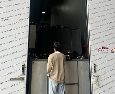 선별장 창고 입구에서 검은색 수거 봉투 더미를 바라보고 있는 오늘수거 이사의 뒷모습