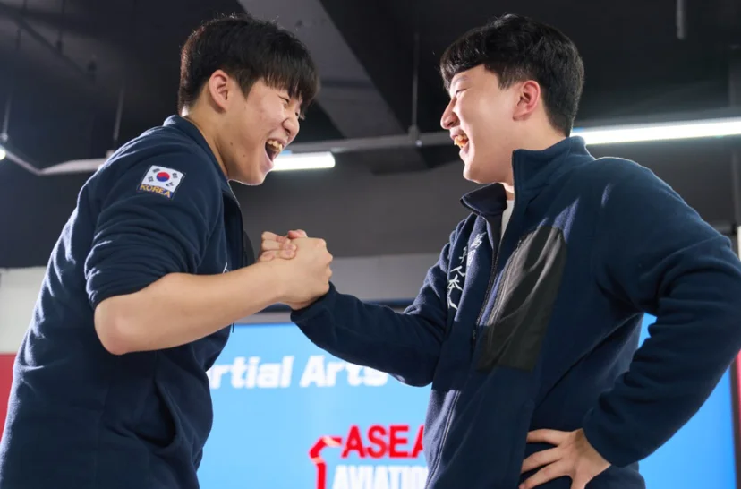 푸른 운동복 차림 두 사람이 마주 서서 손을 잡고 있는 모습