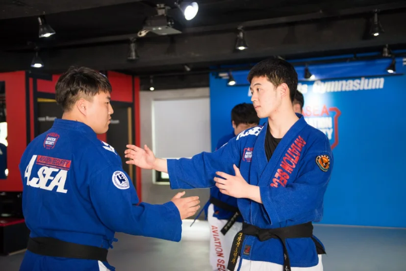 푸른 도복 차림 두 사람이 서로 마주 보고 팔을 뻗고 있는 모습