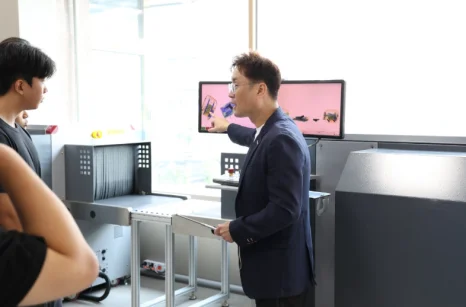 교사가 장비 옆에서 학생에게 설명하는 모습