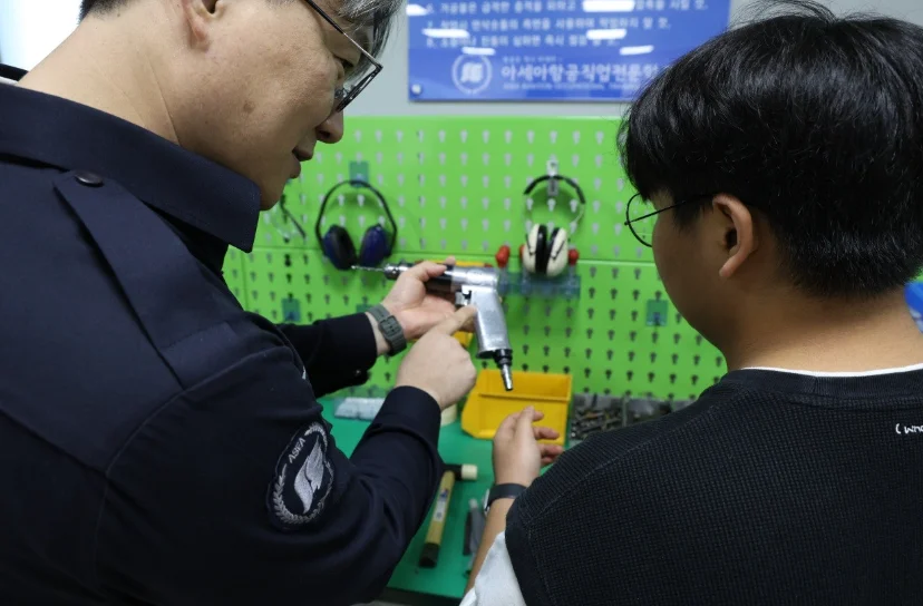 두 사람이 작업대 앞에서 측정 도구를 함께 들여다보고 있는 모습