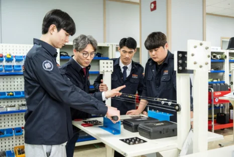 항공기 엔진 장비 앞에서 설명을 듣는 학생들