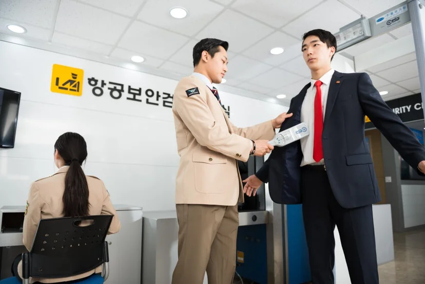 검색 실습실에서 두 사람이 정장 차림 사람의 팔과 몸 주변을 살피고 있는 모습