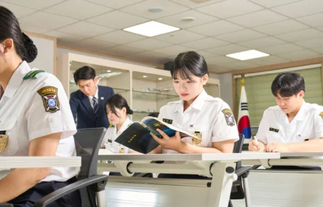 흰 제복 차림 학생들이 교실에서 책을 읽는 모습