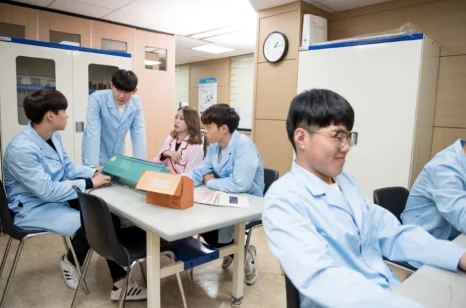 컴퓨터를 사용하는 학생들과 뒤쪽 책상에서 책을 보는 학생들