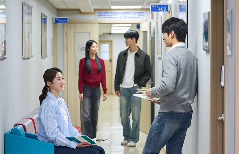 복도 의자에 앉은 두 명과 서 있는 두 명이 대화하는 모습