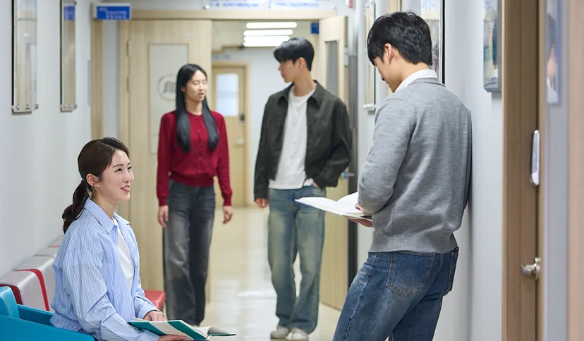 복도 의자에 앉은 학생과 서 있는 학생들이 대화하는 모습