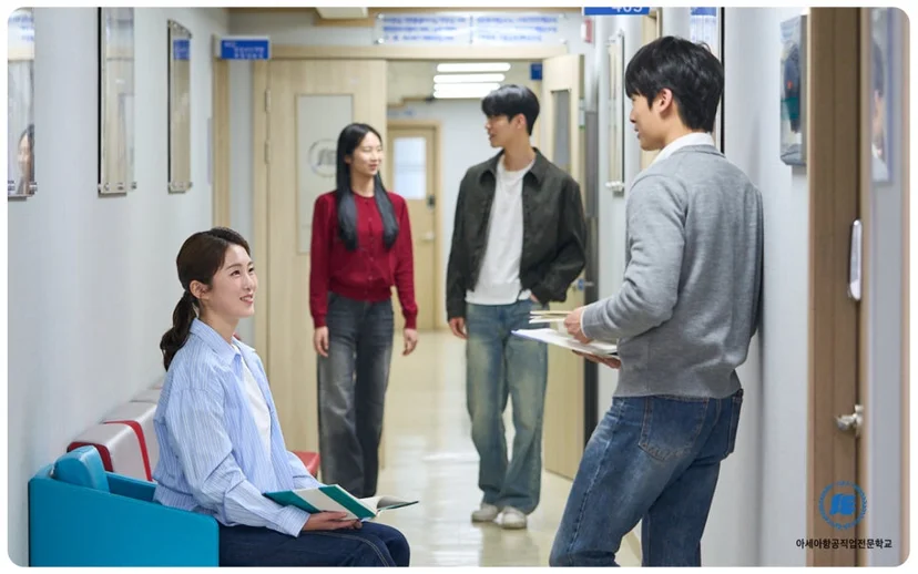 복도에서 의자에 앉은 학생과 서 있는 학생들이 대화하는 모습