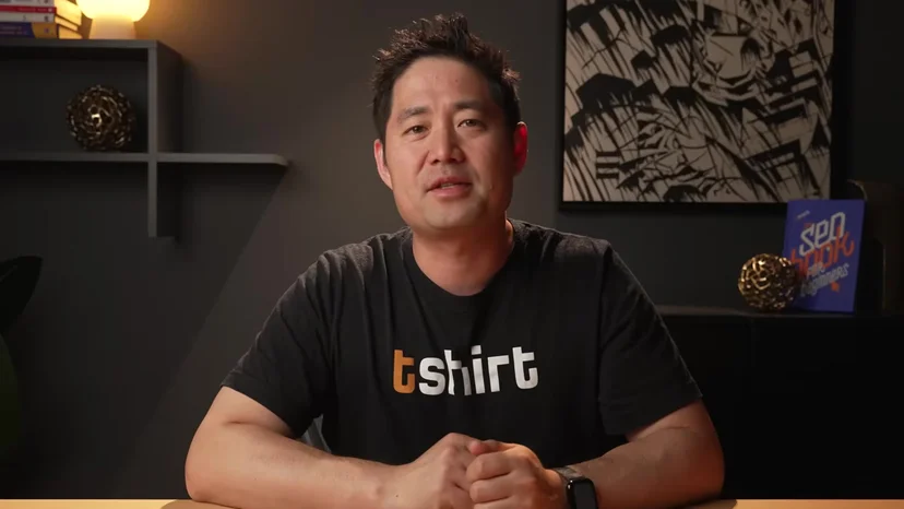책장이 있는 방에서 카메라를 보고 설명하는 진행자