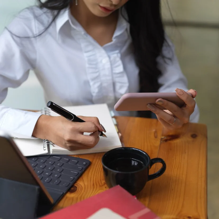 휴대폰 화면을 보며 노트에 내용을 적는 손, 협박 대화와 계좌 정보를 기록으로 남기는 일