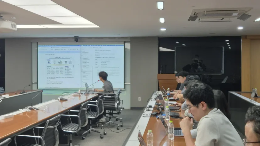 JB금융지주 교육 2회차, 스크린에 PRD 문서를 띄워 설명하고 임직원이 노트북으로 실습하는 모습