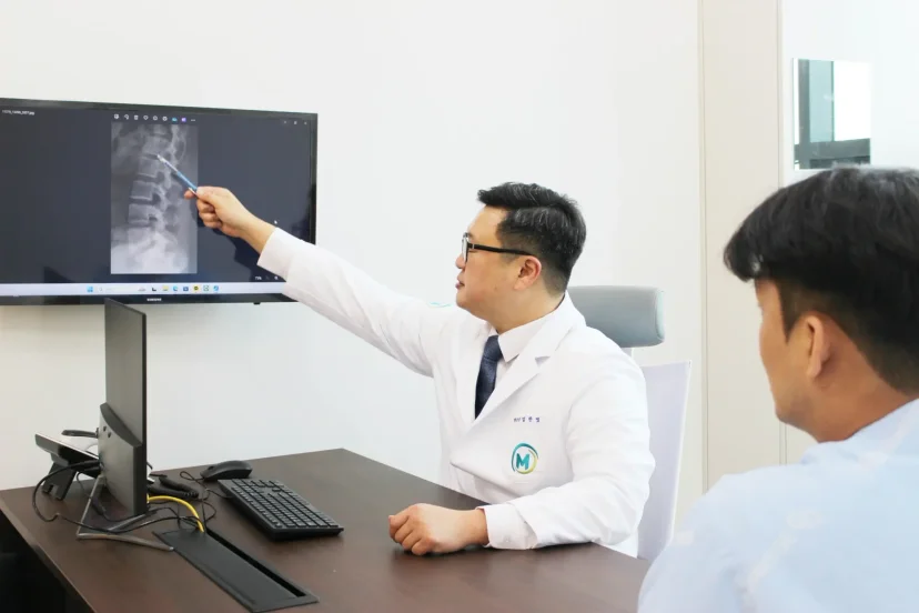 척추관협착증 비수술 진료|척추 X-ray 영상을 보며 환자를 진료하는 임한빛 원장