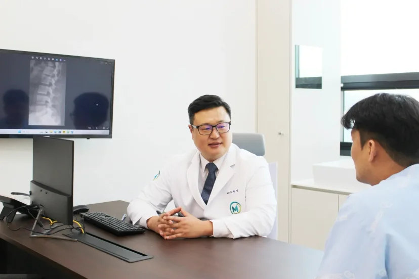 건설현장 산재 치료|척추 엑스레이를 보며 환자와 상담 중인 의사 임한빛