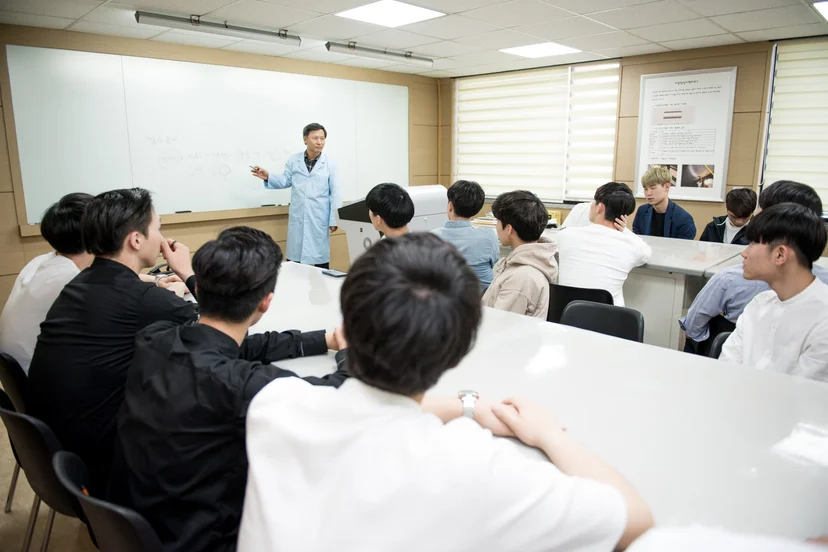 강의실에서 칠판 앞 교수의 이론 수업을 듣는 학생들
