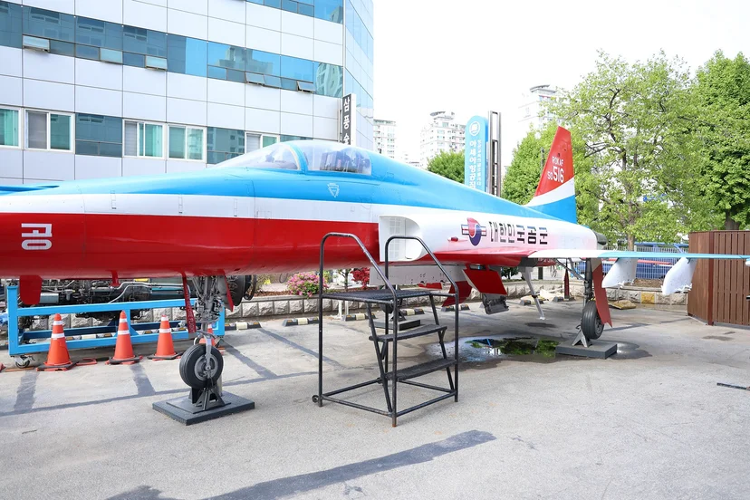 학교 건물 앞에 전시된 항공기와 주변 실습 공간