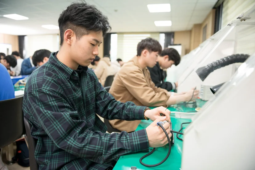 회로판에 측정기를 대고 점검하는 학생