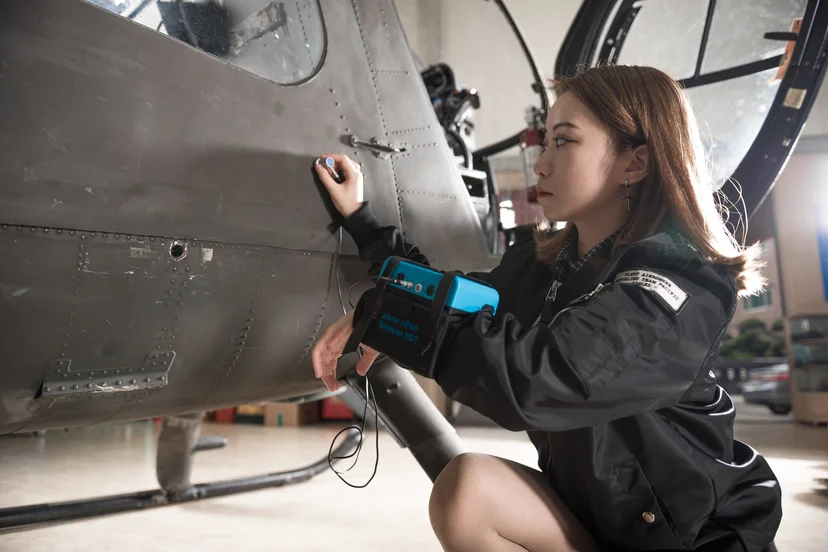 휴대용 검사 장비를 들고 항공기 외부 표면을 살펴보는 모습