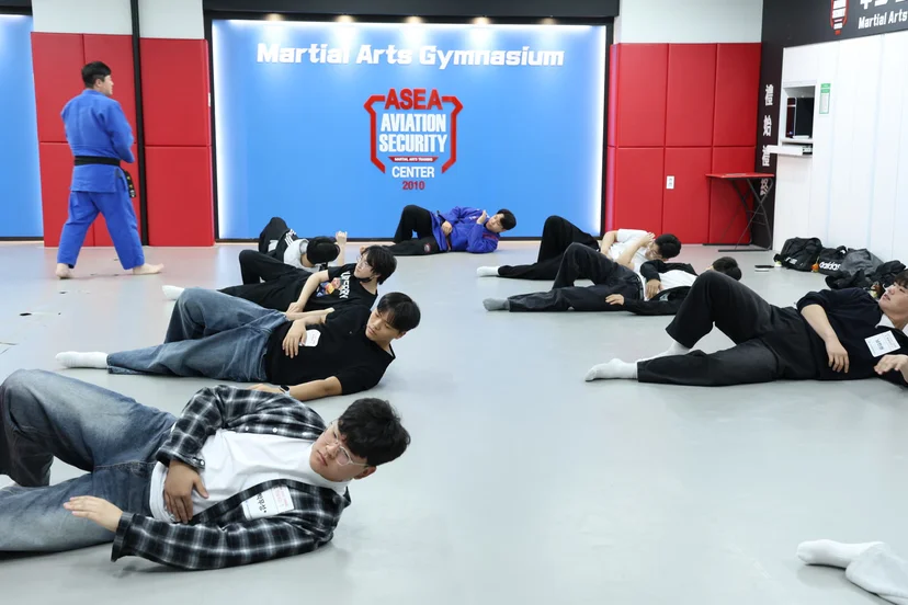 실내 무도 훈련 공간에서 지도하는 사람과 매트 위에서 동작을 연습하는 사람들