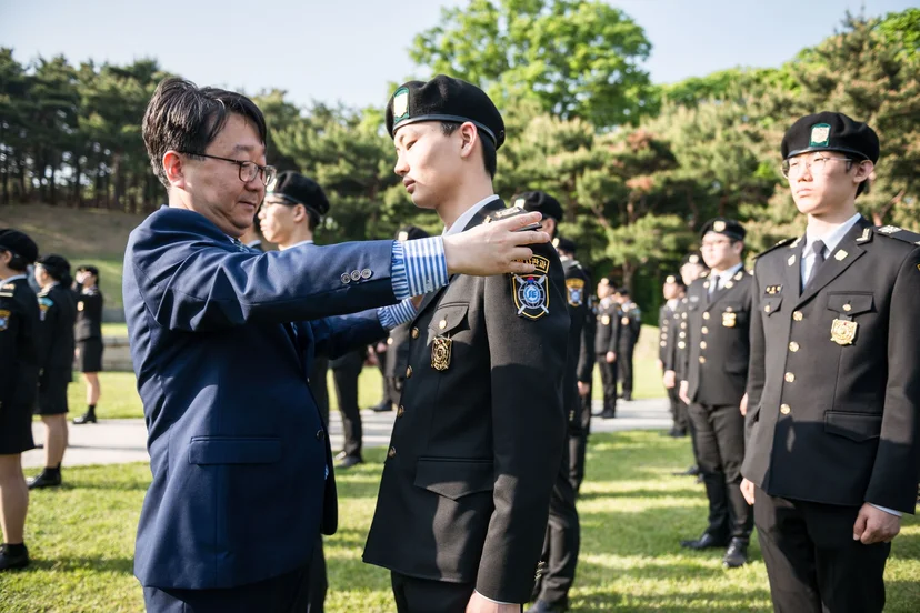 야외에서 제복의 어깨 부분을 정돈하는 모습