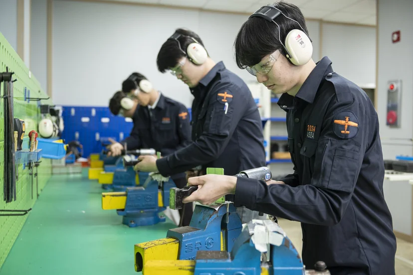 귀 보호구를 착용하고 작업대에서 공구를 사용하는 모습
