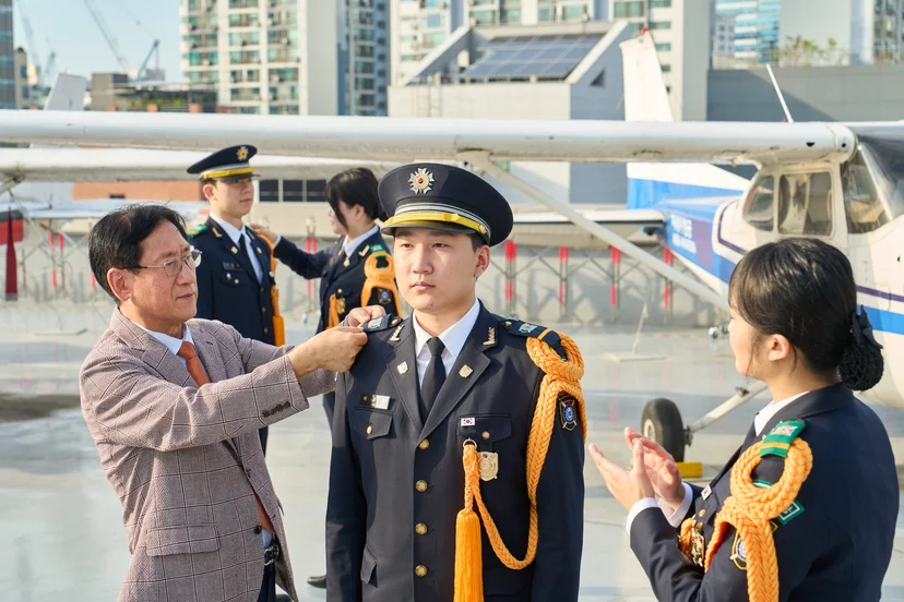 야외에서 제복의 어깨 부분을 정돈하는 모습